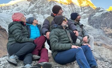 A group of trekkers admiring the golden sunrise over snow-capped peaks at Annapurna Base Camp.
