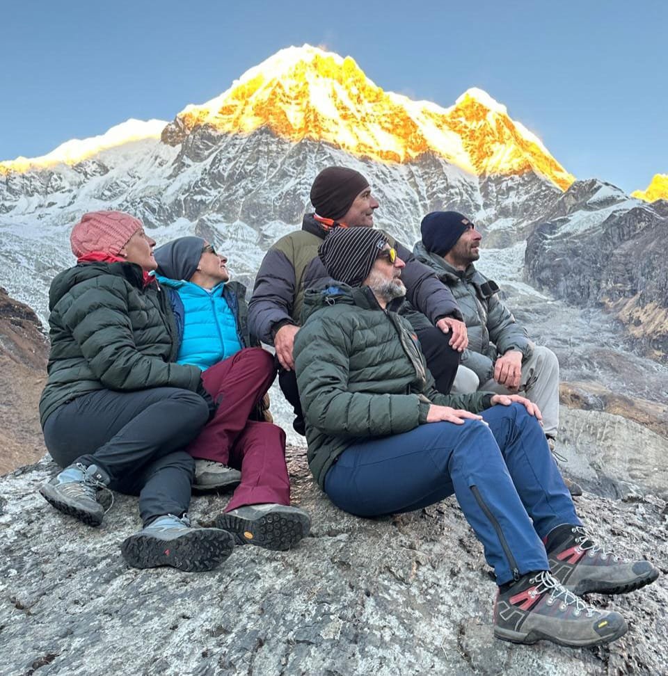 A group of trekkers admiring the golden sunrise over snow-capped peaks at Annapurna Base Camp.