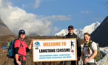 Trekkers arrive at "Welcome to Langtang" sign, deeper into their Nepal mountain trek within Langtang Valley.
