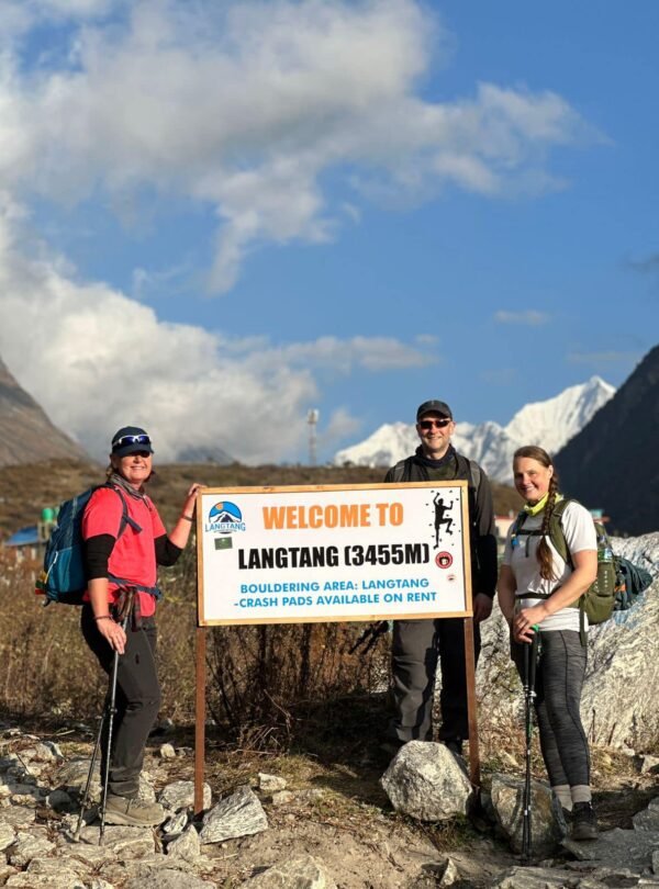 Trekkers arrive at "Welcome to Langtang" sign, deeper into their Nepal mountain trek within Langtang Valley.