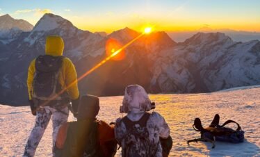 Climbers enjoying the sunrise view from the snowy summit of Mera Peak.